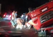 Caminhão que levava refrigerantes tomba em rodovia e população saqueia carga enquanto motorista aguarda atendimento médico